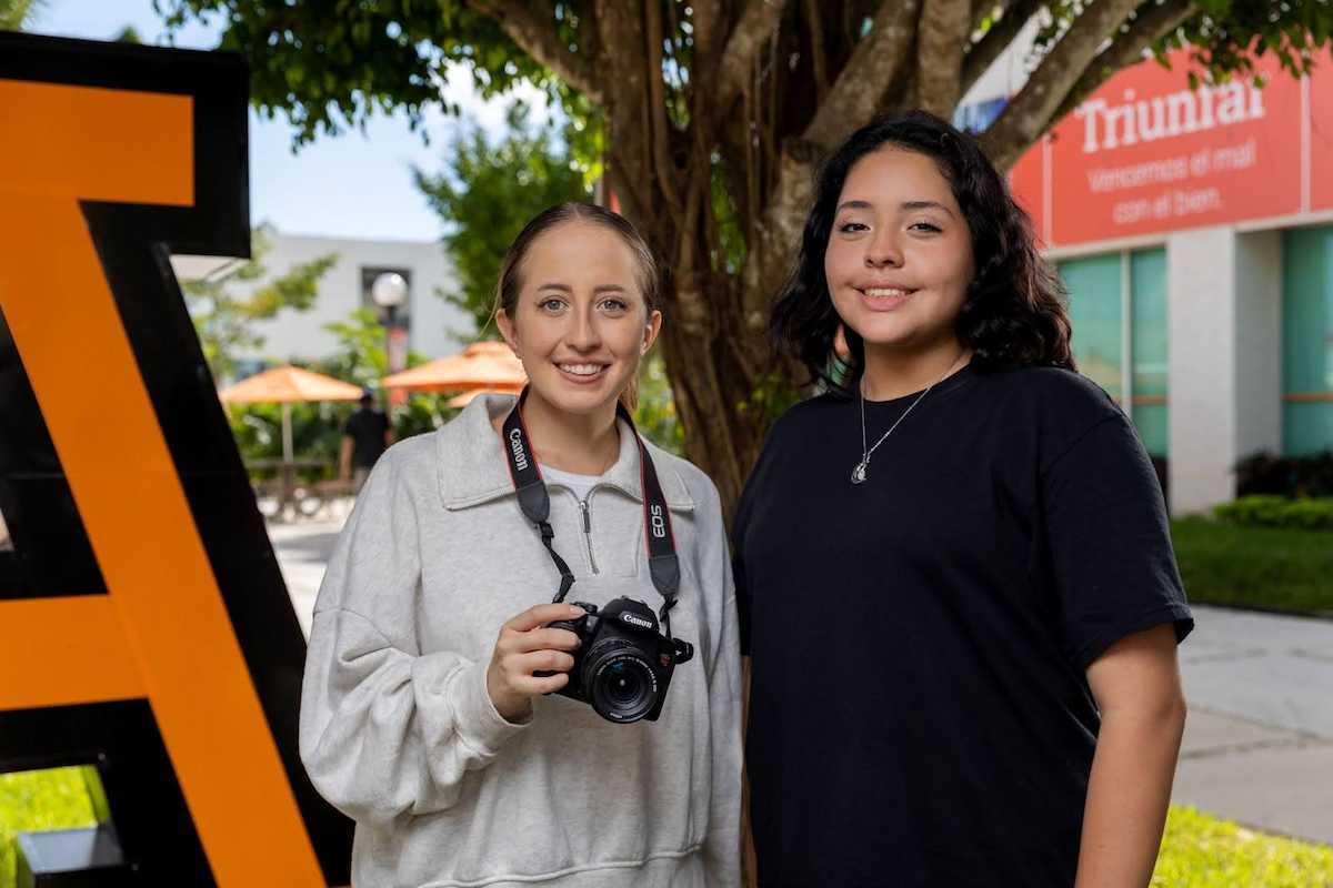 2 alumnas de la licenciatura en Comunicación en el campus de la Anáhuac, una alumna sostiene una cámara.